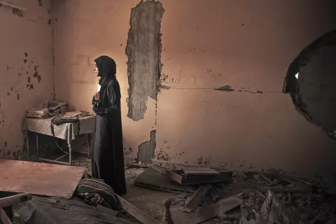 Fatima Asfour stoji sredi ruševin svojega stanovanja v Khan Younisu v Gazi. V rokah drži fotografiji svojih dveh sinov, ki sta septembra 2014 prebežala iz povojne Gaze. Oba, Ramez (26) in Ahmed (25), naj bi bila mrtva po potopitvi ladje ob obali Malte. Do danes še ni prejela nobenih uradnih novic o njuni usodi. Khan Younis, Gaza, 27. september 2014. / Foto: Matic Zorman