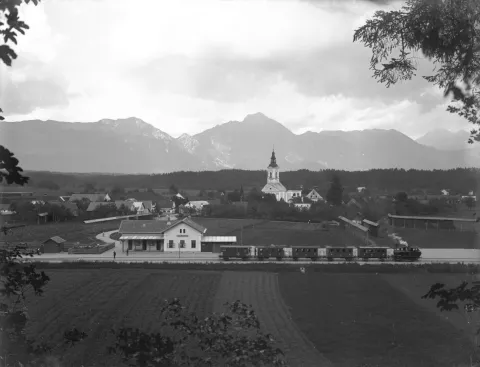 Fotografija železni&scaron;ke postaje Naklo, čas nastanka med letoma 1908 in 1910, ko je &scaron;e delovala 17-kilometrska proga Kranj&ndash;Tržič. Klasična krajevna panorama je verjetno fotografirana po naročilu, saj je fotograf skrbno izbral mesto postavitve kamere, počakal na trenutek odhoda potni&scaron;kega vlaka, da ni zastrl pogleda na postajo, pa tudi na ustrezno vreme. Lokomotiva na fotografiji je bila kot ena od le treh iz serije izdelana v tovarni Krauss v Linzu v Avstriji. Namenjena je bila prav vleki lažjih vlakov na kraj&scaron;ih lokalnih progah, med drugim navaja Ale&scaron; Bedič iz Dru&scaron;tva za raziskovanje in proučevanje voja&scaron;ke in tehni&scaron;ke dedi&scaron;čine Vr&scaron;ič, ki je natančno raziskal ozadje te zanimive fotografije. / Foto: Alojz Vengar, arhiv MRO