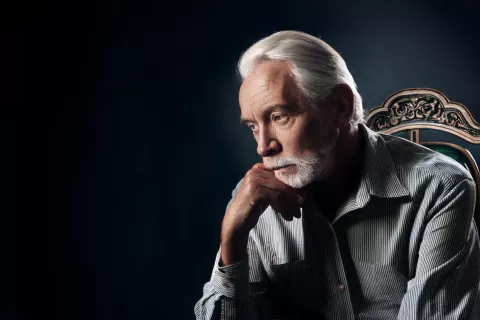 Star mo&scaron;ki sedi v temni sobi in razmi&scaron;lja / Foto: Adobe Firefly