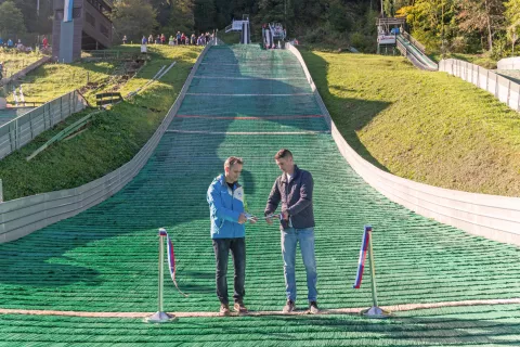 Predsednik Skakalnega kluba Triglav Kranj Sa&scaron;o Komovec in podžupan MOK Janez Černe sta simbolično prerezala vrvico pod prenovljenima skakalnicama. / Foto: Primož Pičulin