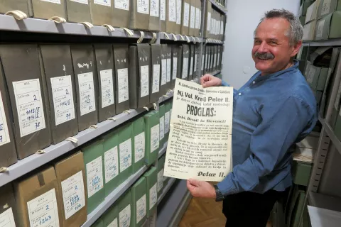 Dr. Gorazd Stariha z razglasnim plakatom, na katerem kralj Peter II. sporoča, da s 27. marcem 1941 zaradi nestabilnih razmer v Evropi v takratni Kraljevini Jugoslaviji prevzema popolno oblast. / Foto: Igor Kavčič / Foto: 