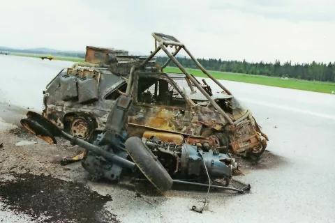 Ostanki avtomobila na letališču Brnik, v katerem sta zgorela avstrijska novinarja. Ko sta se vozila po letališki pisti, so ju zadeli izstrelki tankov JLA; 28. junij 1991 / Foto: Marjan Mikluš / Foto: 