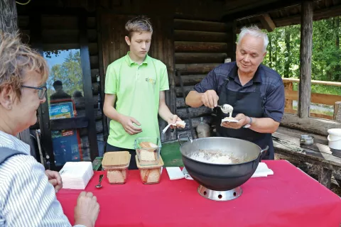 Medtem ko je Milan Milošič razdeljeval jezerski masunjek, smo izvedeli še marsikaj zanimivega o tej močni jedi. Pomagal mu je vnuk Žiga. / Foto: 