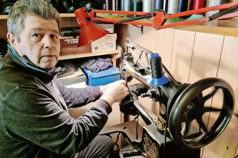 Tomo Mladenović pri delu uporablja sto štirideset let staro singerico. »Ta me bo preživela,« je prepričan eden zadnjih jeseniških čevljarjev. / Foto: 