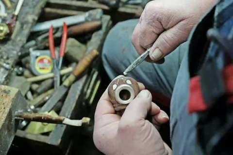 Mojster Lotrič je krepak možak, za katerega bi si človek komaj predstavljal, da zmore opravljati tako natančno delo, kot je oblikovanje intarzij iz školjčne biserovine. / Foto: Gorazd Kavčič / Foto: 